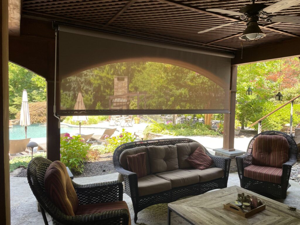 Retractable rolling screen provides shade for an outdoor patio.