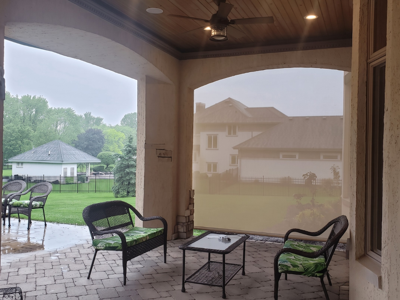 An outdoor space with a vaulted roof and a retractable screen installed to protect from wind and other elements.