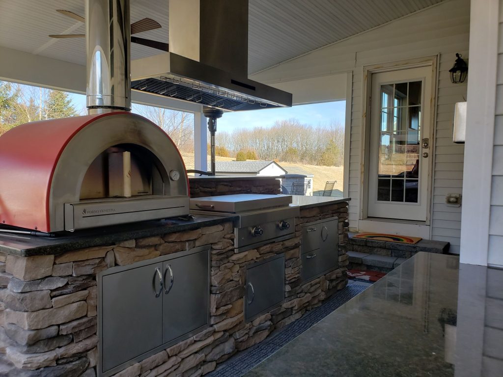 Outdoor kitchen with a pizza oven and stone base