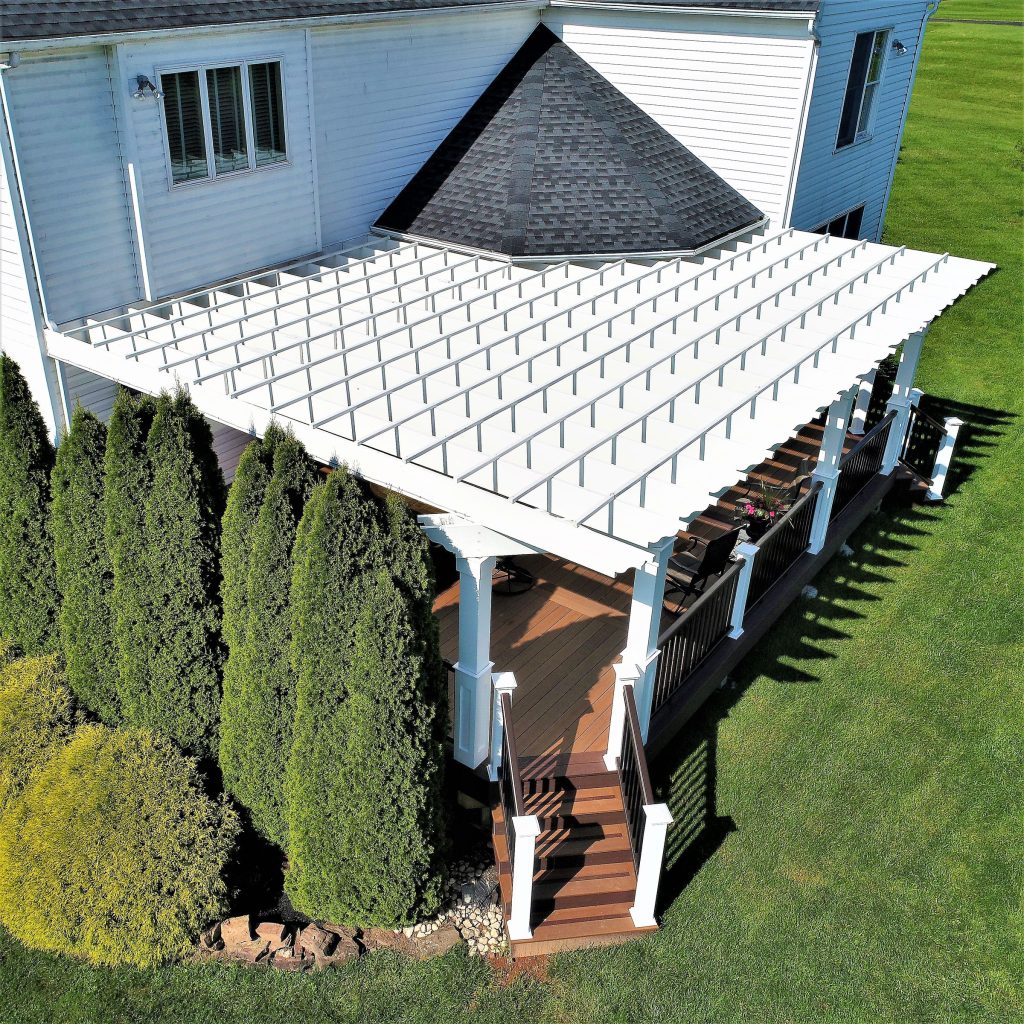 White pergola over a deck framed by evergreens