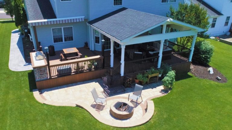 Aerial view of a covered deck beside a paver patio and fire pit